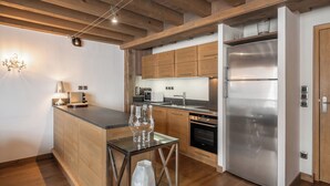 Eine moderne Küche mit Holzschränken, einem Edelstahlkühlschrank und einer Kochinsel mit Glasplatte sowie Dekorationselementen.