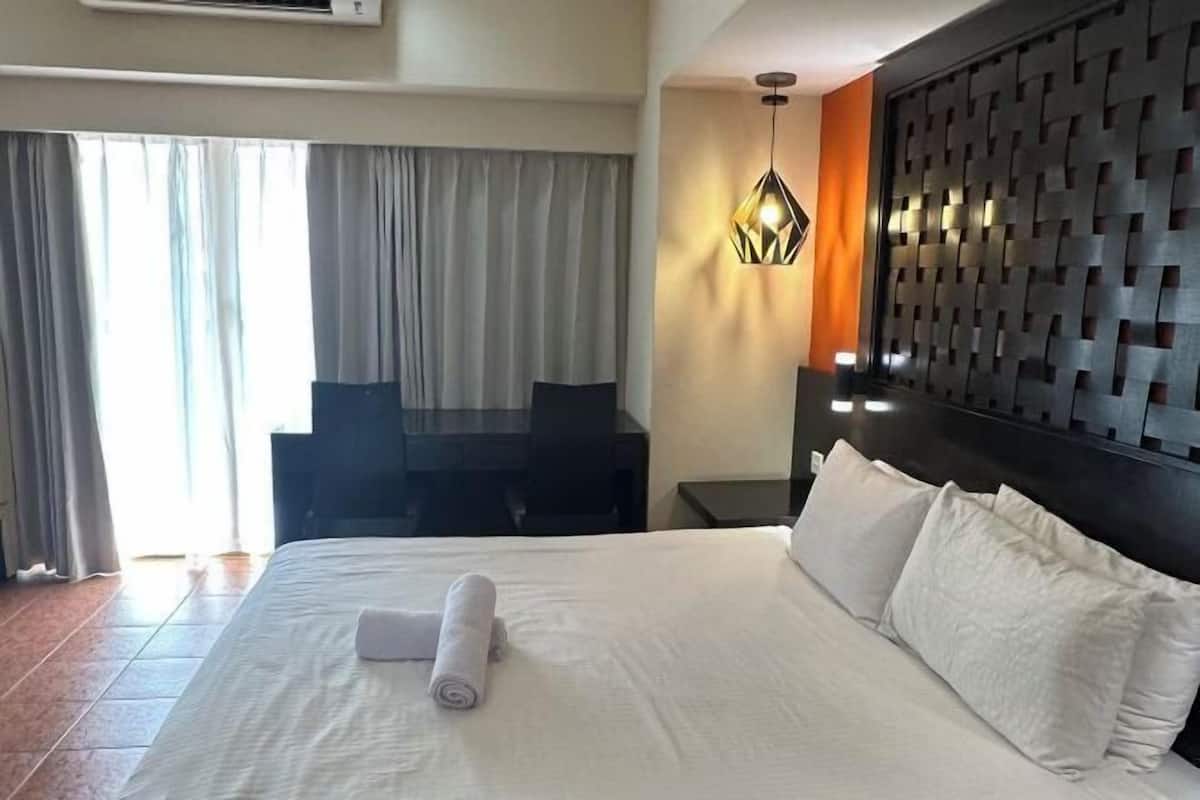 Una habitación de hotel con una cama grande, un escritorio y una silla.