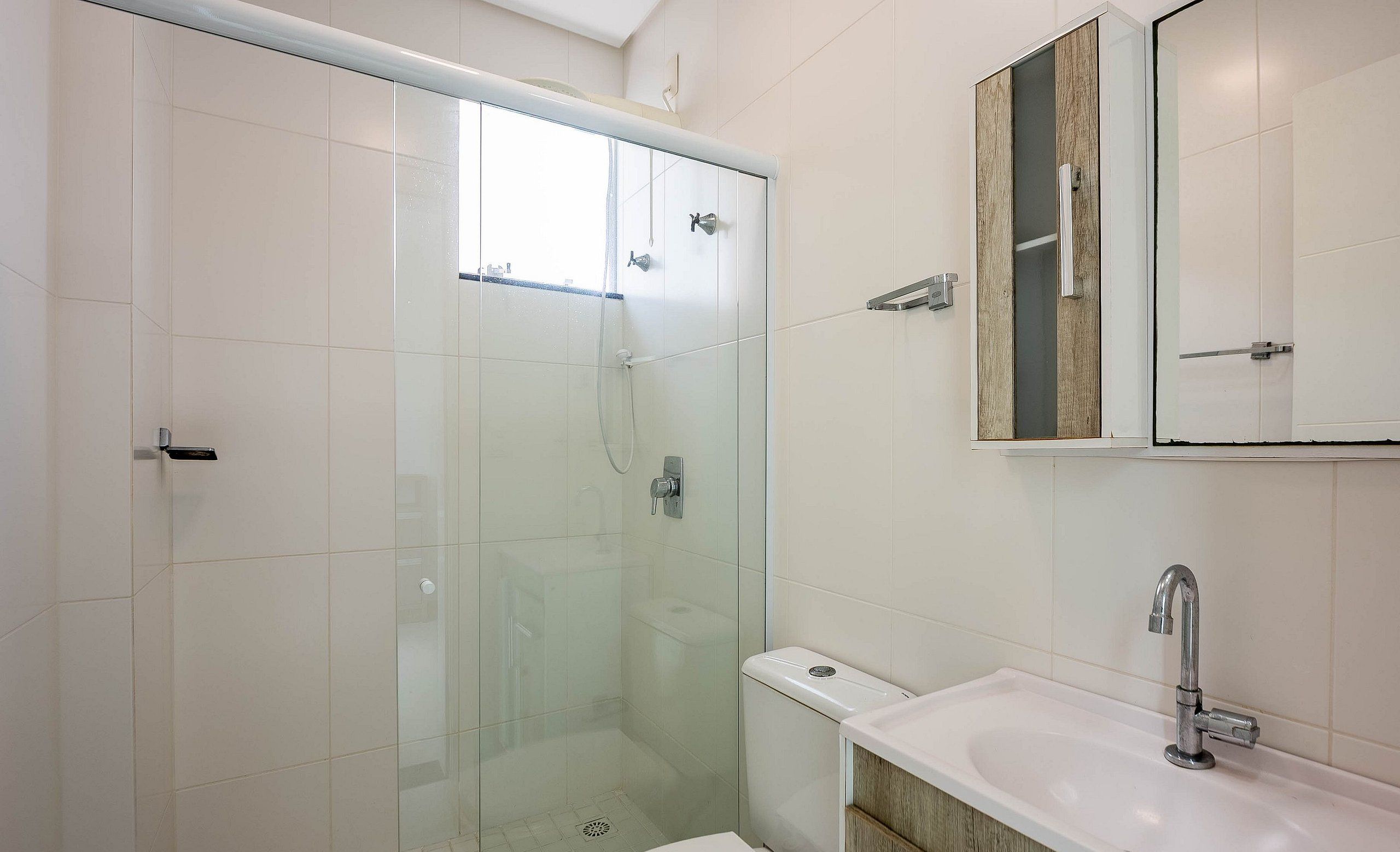 A modern bathroom with a glass-enclosed shower, a toilet, and a sink with a wooden vanity.