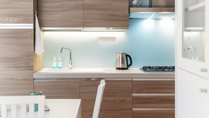 Een moderne keuken met houten kastjes, een RVS waterkoker en een gasfornuis.