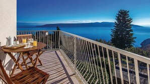 A balcony with a table set for breakfast, overlooking a scenic view of a body of water and distant mountains. - Holiday Home Brsec-Two Bedroom Holiday Home with Sea View (Brsec)