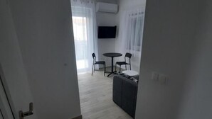 A modern living room with a sofa, two chairs, a small table, and a flat-screen TV mounted on the wall. - Apartments Matković - Two Bedroom Apartment1 (Vir)