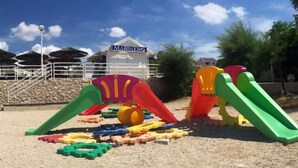 A playground with colorful play structures and a building labeled "MARINERO" in the background. - Apartments Matković - Two Bedroom Apartment1 (Vir)