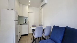 A compact kitchen with white cabinets, a dining table with four chairs, and a blue sofa. - Apartments Ivankovic - One Bedroom Apartment with Terrace (Zaton)