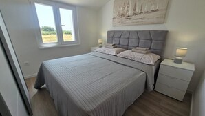 A bedroom with a large bed, a window, a nightstand, and a painting on the wall. - Apartments Ivankovic - One Bedroom Apartment with Terrace (Zaton)