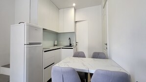 A compact kitchen with white cabinets, a built-in sink, and a small countertop. There is a dining table with two chairs and a coffee maker. - Apartments Ivankovic - One Bedroom Apartment with Terrace (Zaton)