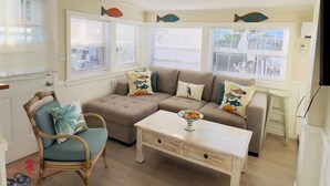 A cozy living room with a sectional sofa, a wooden coffee table, and a wicker chair. - Fisherman's Cottage at Matlacha (Matlacha)