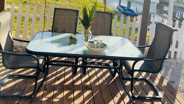 A covered outdoor seating area with a table, chairs, and a view of a lake. - Fisherman's Cottage at Matlacha (Matlacha)