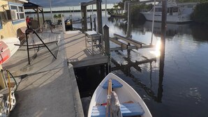 A dock with a small boat, a covered seating area, and a building with an air conditioning unit. - Fisherman's Cottage at Matlacha (Matlacha)