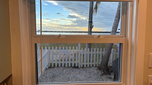 A window with a view of a white picket fence and a tree, and a clear sky. - Fisherman's Cottage at Matlacha (Matlacha)