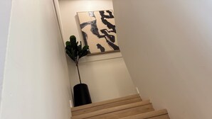 Eine Holztreppe mit einem Blumentopf und einem abstrakten Kunstwerk an der Wand.