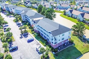A multi-story residential building with a parking lot in front.
