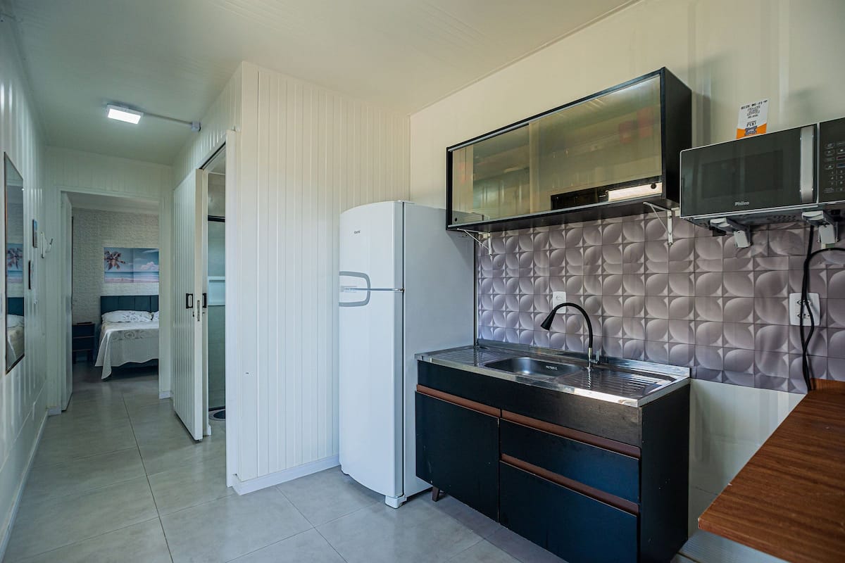 A compact kitchen with a refrigerator, microwave, and sink.