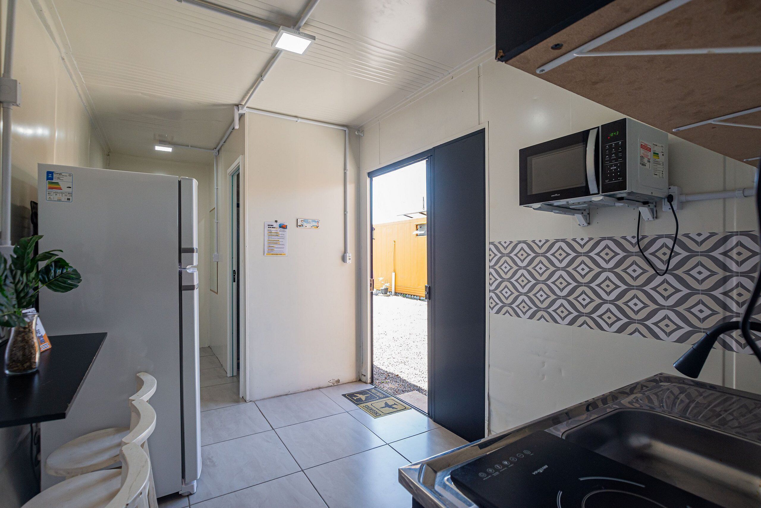 A compact kitchen with a microwave, refrigerator, and sink.