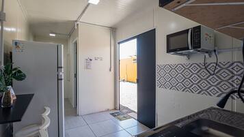 A compact kitchen with a microwave, refrigerator, and sink.