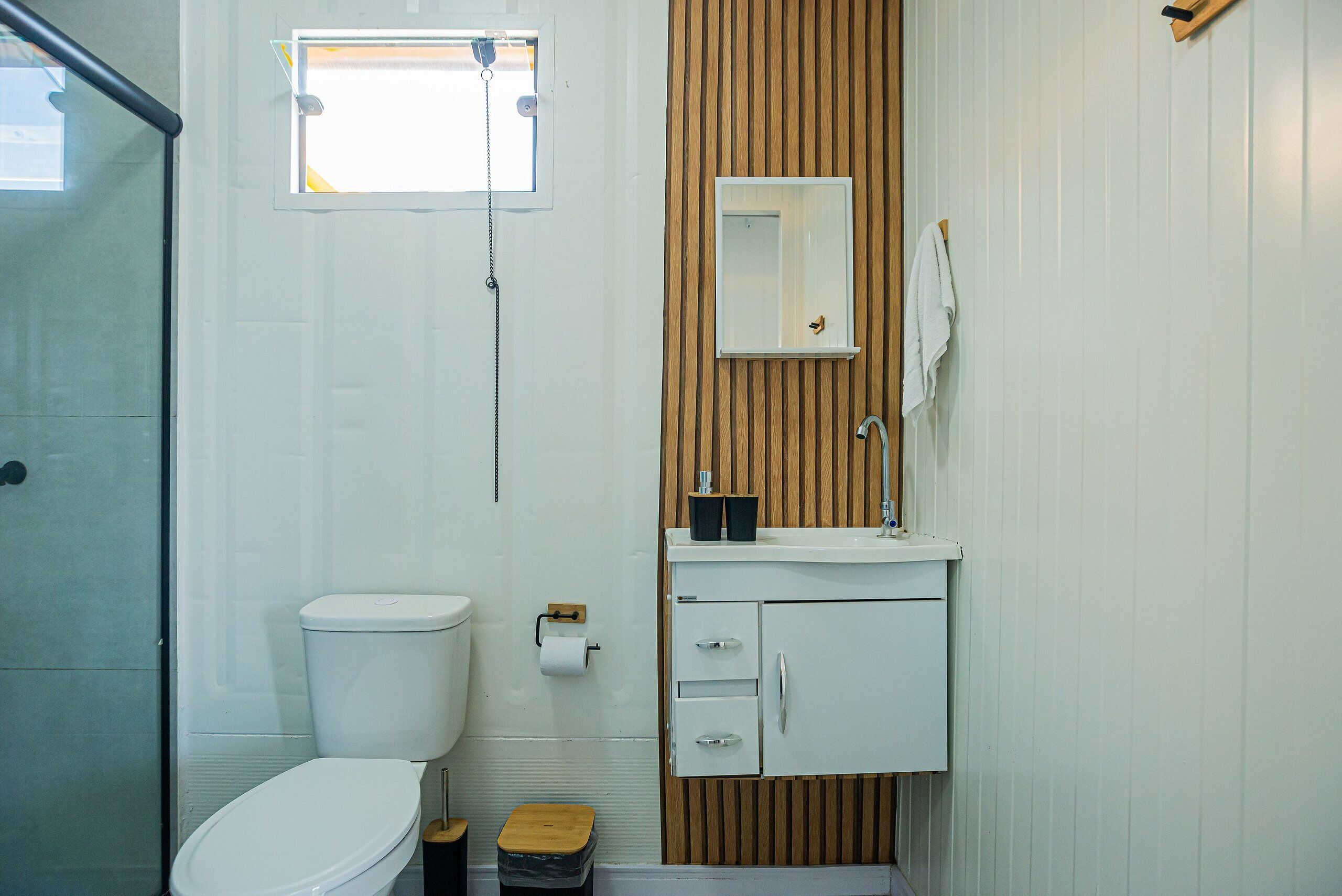 A bathroom with a toilet, a sink, a mirror, and a shower.