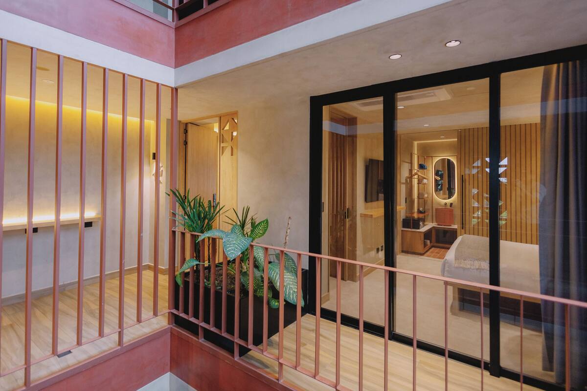 A modern hotel interior with a balcony, a reception area, and a living space with a sofa and a TV.
