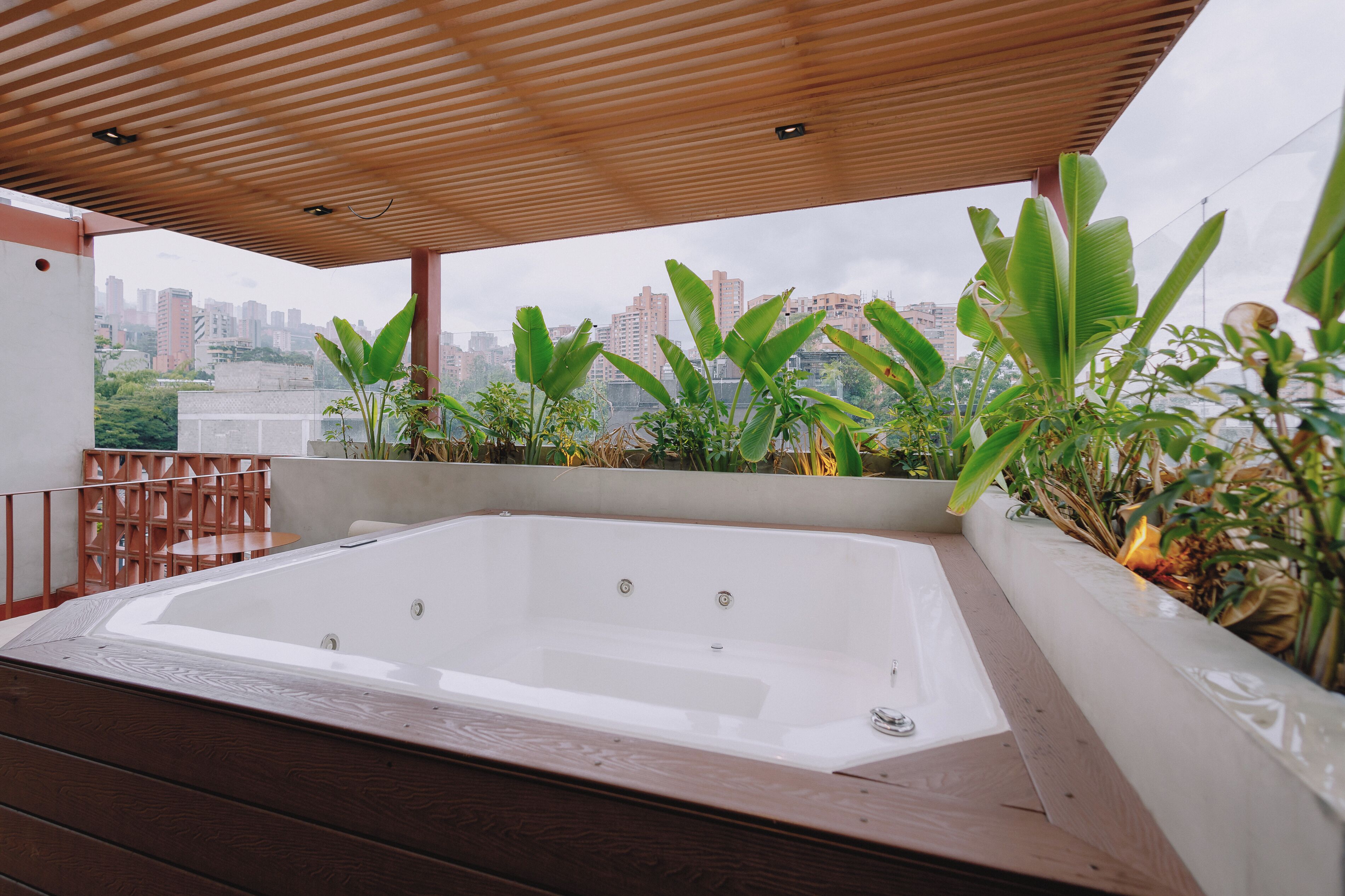 Terraza en la azotea con jacuzzi, cubierta de madera y plantas en macetas.