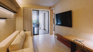 A modern living room with a sofa, a wooden table, and a flat-screen TV mounted on the wall.