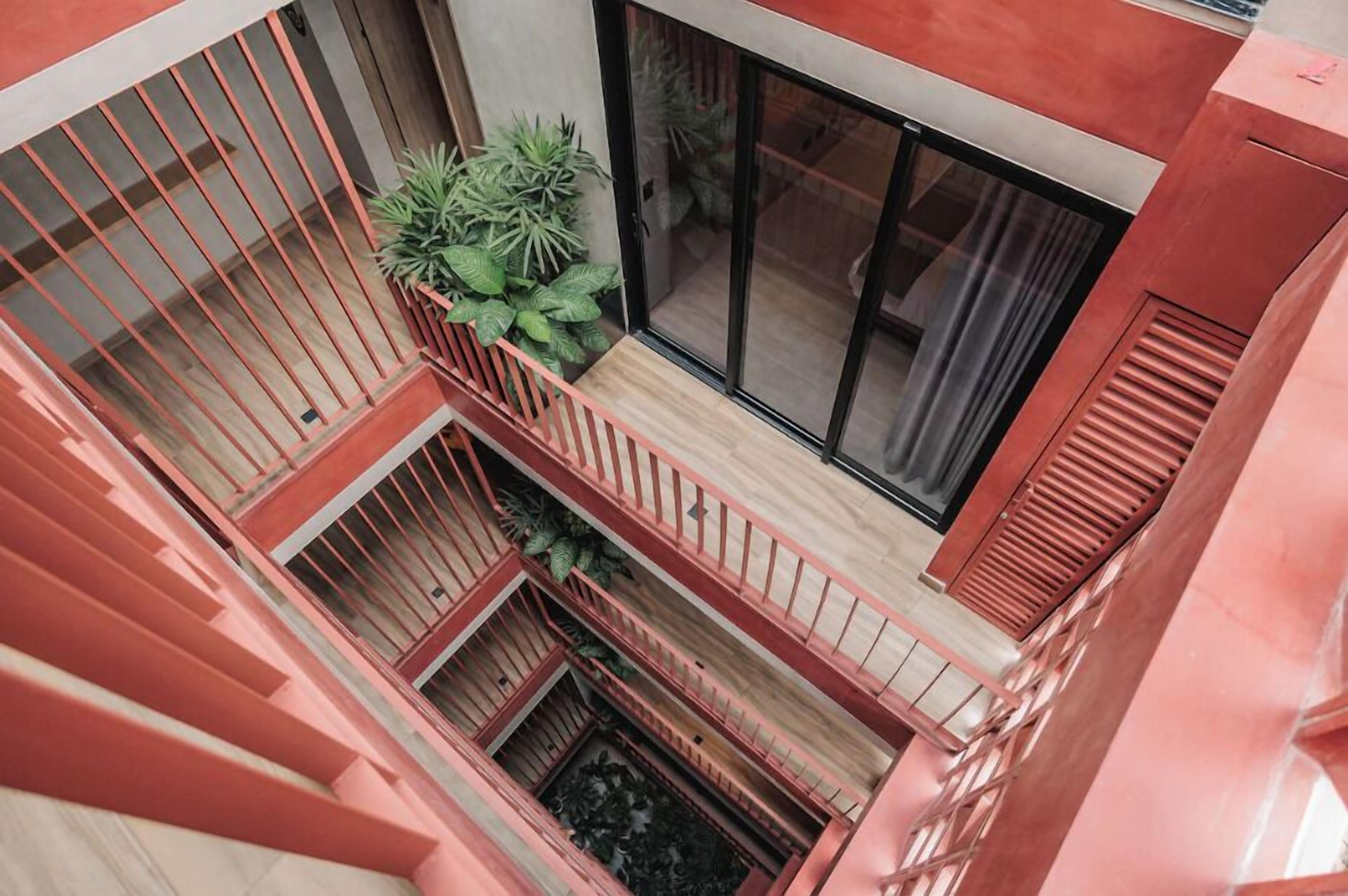 A multi-level building with a red exterior, wooden balconies, and large sliding glass doors.