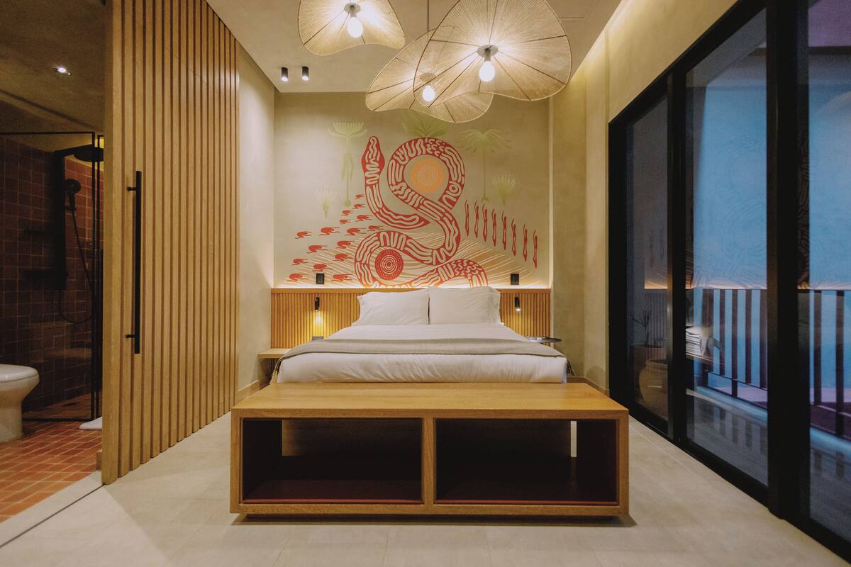 A modern bedroom with a bed, wooden headboard, and a large window.