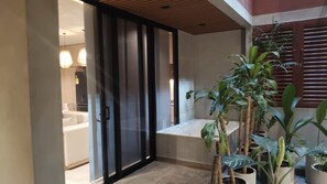 A modern bathroom with a glass door, a bathtub, and a potted plant. - Kuuna Medellín By Be Host (Medellín)