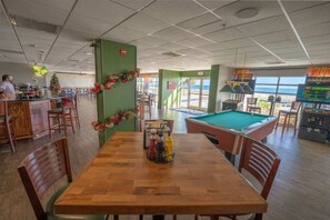 Une table de billard, un coin repas et un bar avec vue sur l’océan.