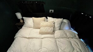 A bed with a white quilt and two decorative pillows. - Deluxe camping in newly remodeled airstream! (honey Grove)