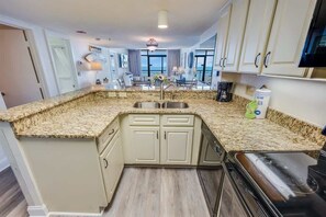 A kitchen with granite countertops, a stainless steel sink, and a built-in oven.