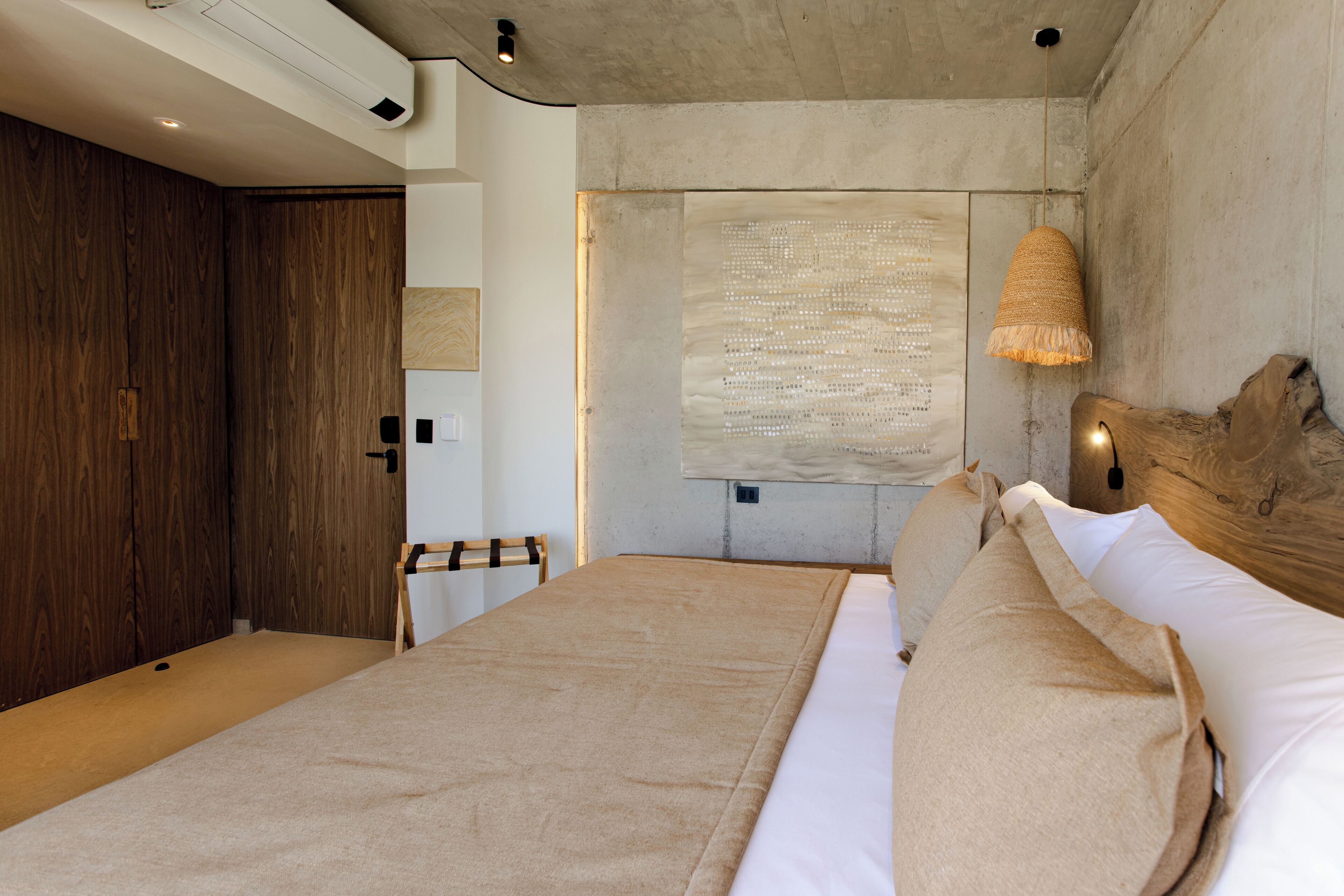 A bedroom with a large bed, wooden wardrobe, and a hanging light fixture.