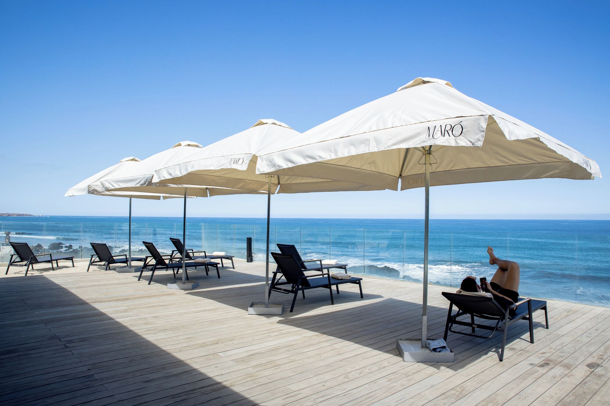 A deck with lounge chairs and umbrellas overlooking the ocean.