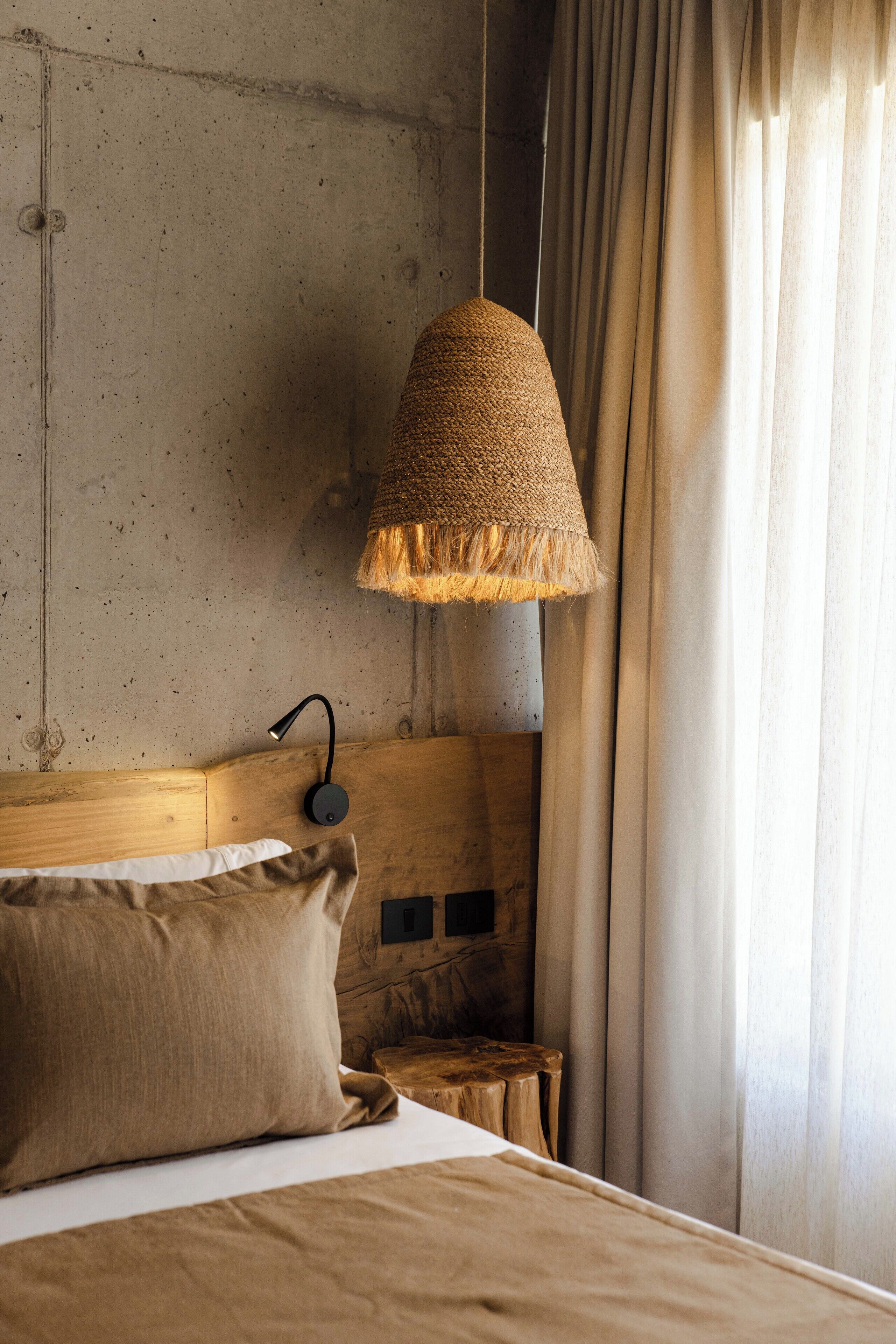 A bedroom with a wooden headboard, a hanging lamp, and a bed with a beige pillow.