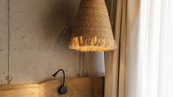 A bedroom with a wooden headboard, a hanging lamp, and a bed with a beige pillow.