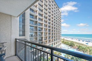 Een hoog hotel met meerdere balkons met uitzicht op een strand.
