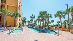 A pool area with palm trees, a sign prohibiting diving, and a building with balconies. - Remodeled 1BR at Caravelle ,Oceanview Suite, Pools (Myrtle Beach)