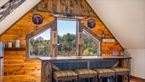 A cozy wooden bar area with a view of the outdoors, wooden walls, and a sign for 'Fireball'.