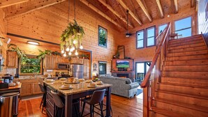 A spacious log cabin interior with a kitchen, dining area, and living room. - The Real McCoy | Epic Views, Hot Tub, Arcade! (Sevierville)