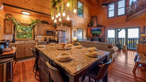A spacious kitchen with granite countertops, a central island, and a dining area. - The Real McCoy | Epic Views, Hot Tub, Arcade! (Sevierville)