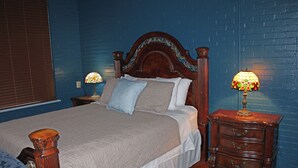 Ein Schlafzimmer mit einem großen Bett, zwei Nachttischen und einem Beistelltischchen mit einer Lampe.