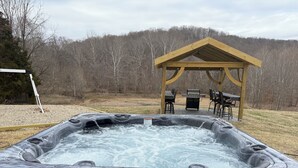 Ein Whirlpool mit einer Holzpergola und Gartenmöbeln im Hinterhof.