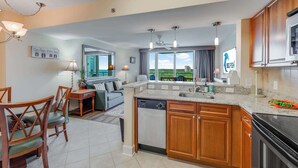 A modern kitchen with wooden cabinets, a dishwasher, and a large window offering a view of the outdoors. - New 2BR at Horizon at 77th with Views,Nice Pools! (Myrtle Beach)