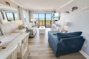 Una sala de estar moderna con un ventanal grande, un sofá, una mesa de centro y un televisor.