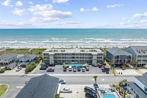 A hotel with a pool, parking lot, and ocean view.