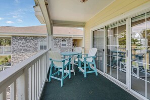 Ein Balkon mit Stühlen und einem Tisch, eine Steinmauer und Blick auf benachbarte Gebäude.
