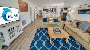 A spacious living room with a large TV, a ceiling fan, and a dining area in the background. - Large 3BR Private Condo - Magnolia Pointe - Pools (Myrtle Beach)