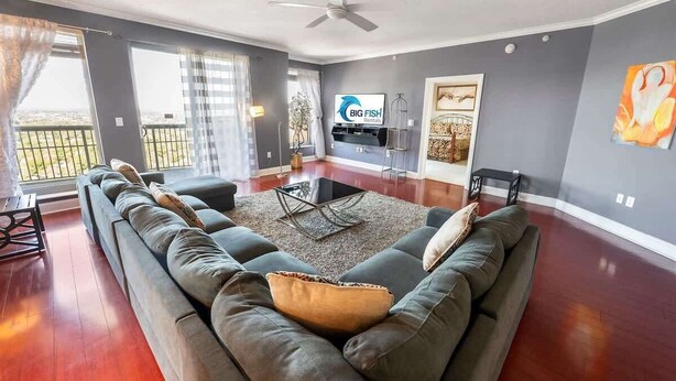 Ein modernes Wohnzimmer mit einem großen grauen Sofa, einem Couchtisch und einem Flachbildfernseher.