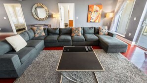 Ein modernes Wohnzimmer mit einem Ecksofa, einem Couchtisch und einem großen Spiegel.