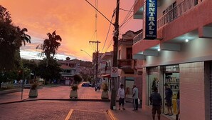 Un hôtel appelé « Hôtel Central », avec une enseigne, une rue pavée de briques et un ciel au coucher du soleil.