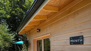 A wooden cabin with a deck, a sign reading "MOUTY", and a potted plant. - "MOUTY": A DELIGHTFUL WOODEN CHALET AT THE EDGE OF THE FOREST (Le Chambon-sur-Lignon)