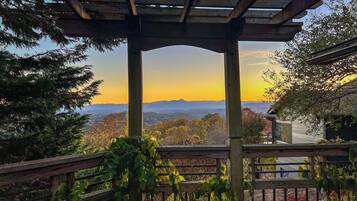 Une pergola en bois offrant une vue sur un coucher de soleil sur les montagnes.